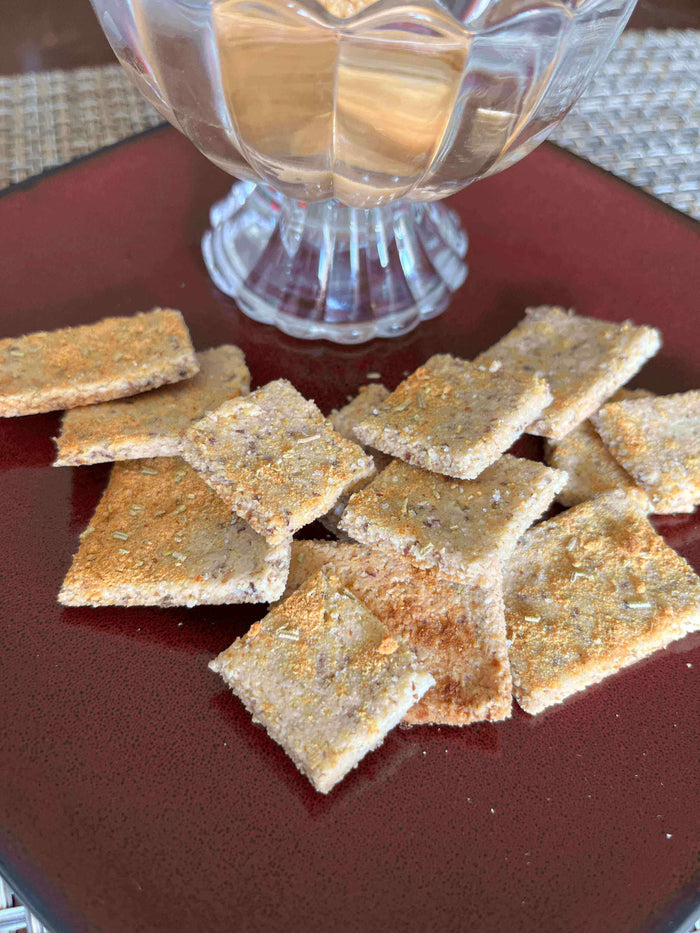 Parmesan Herb Crunchies: Homemade Almond Flour Crackers served with a glass of wine on a red plate.