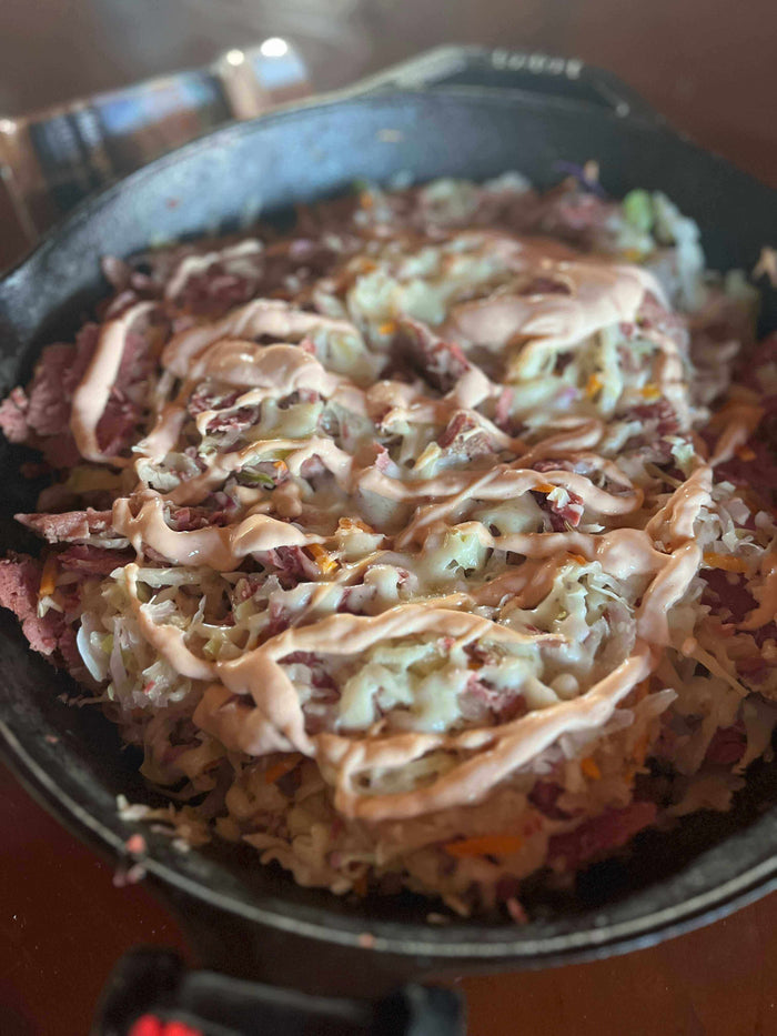 Delicious Reuben in a Bowl featuring corned beef, melted Swiss, and creamy sauce in a skillet.