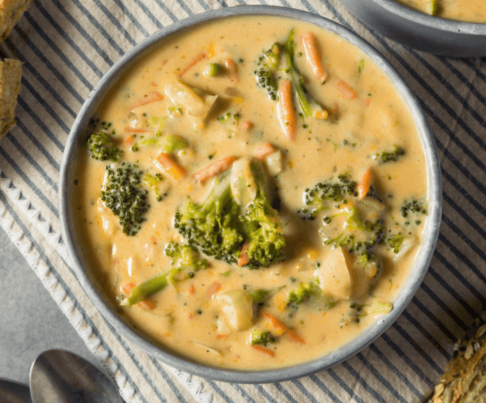 Bowl of 30-Minute Broccoli Cheddar Soup with broccoli and carrots on the table, perfect cozy recipe.