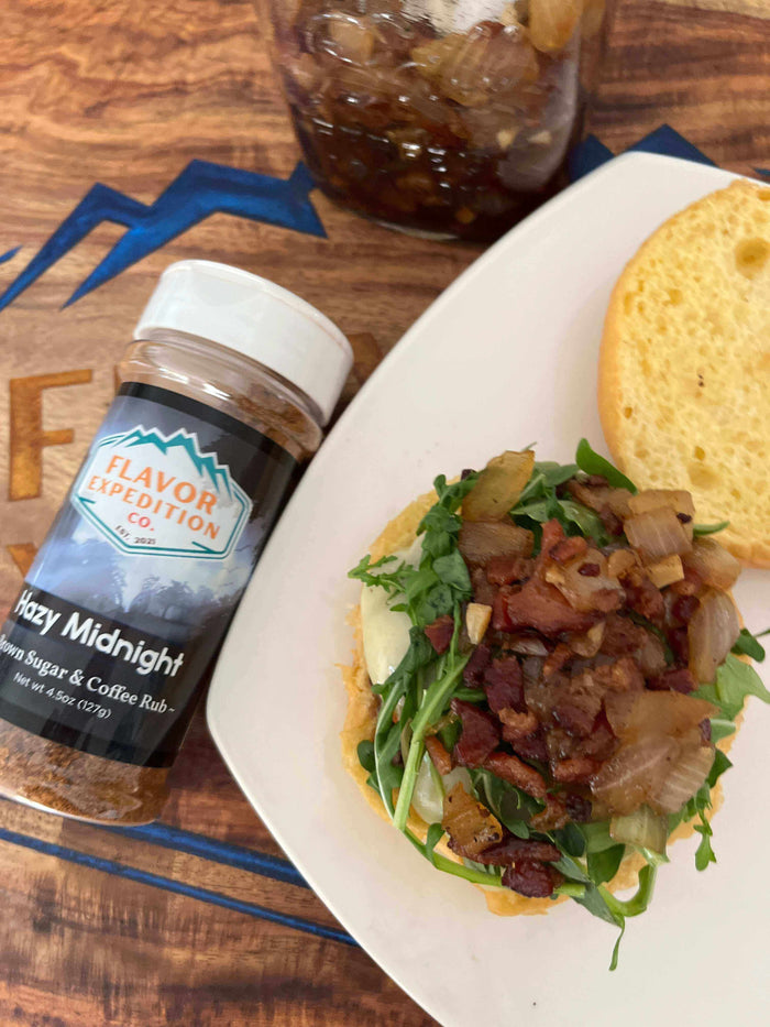 Midnight Ride Blueberry Bison Burger topped with Hazy Midnight spice mix, featuring bacon, greens, and crispy onions.