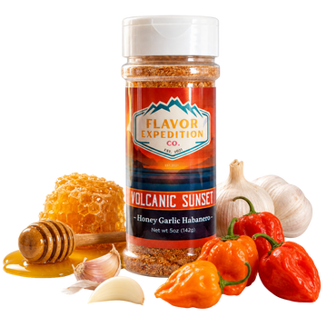 Spice jar labeled 'Flavor Expedition Co. Volcanic Sunset' with peppers, garlic, and honey on a white background