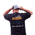 Man wearing a Wildly Delicious T-Shirt from Flavor Expedition Co. showcasing a vibrant logo.