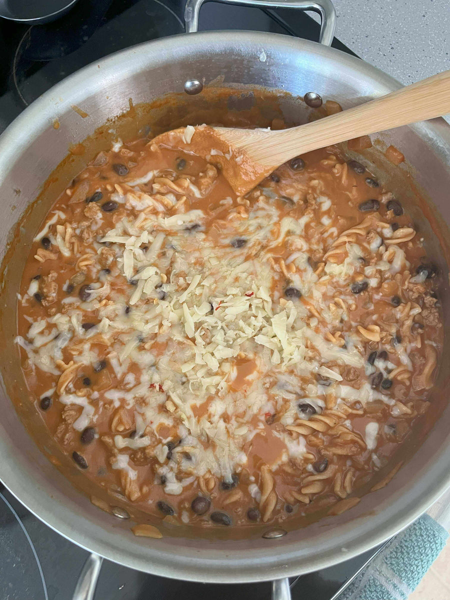 Delicious Turkey Chili Mac & Cheese cooking in a pot, creamy cheese melting over pasta and beans.