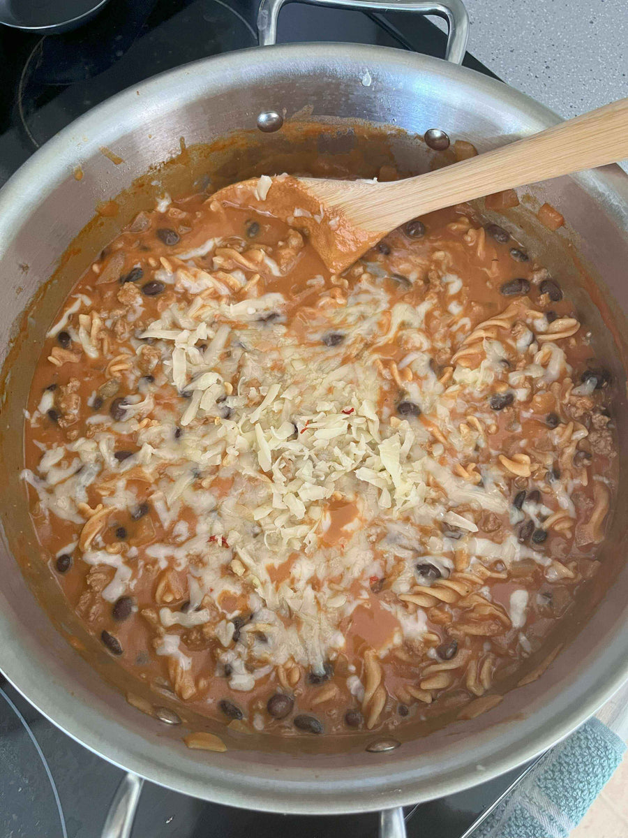 Delicious Turkey Chili Mac & Cheese bubbling in a pan, with melted cheese and black beans, ready to be served.