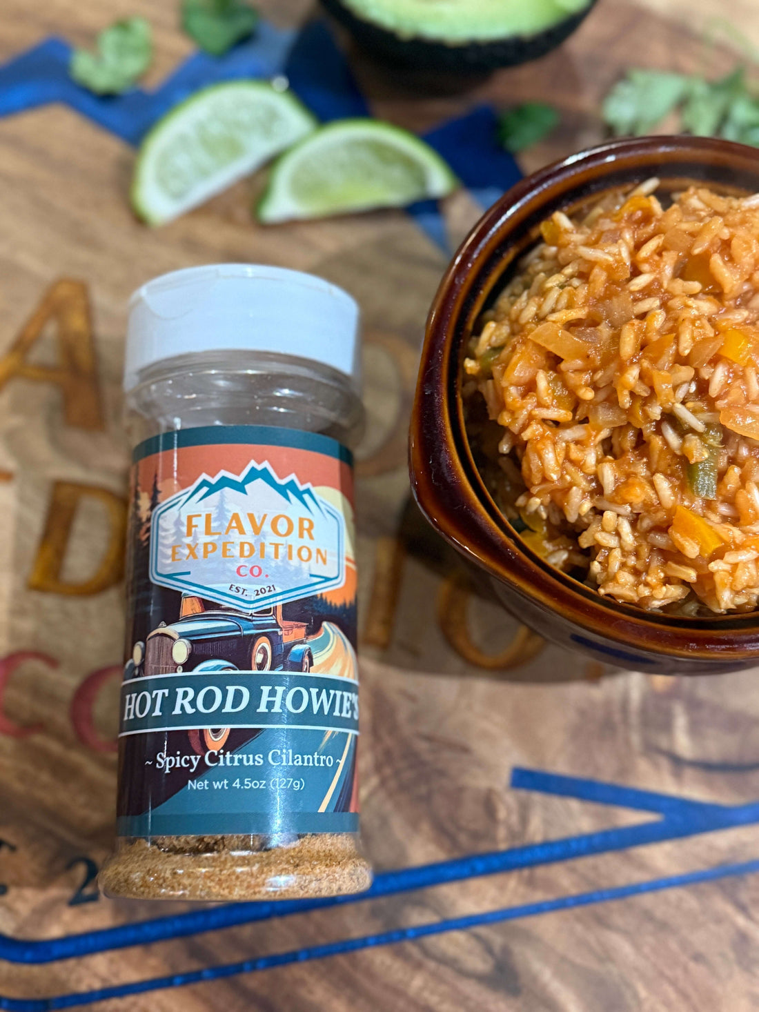Spicy restaurant-style Mexican rice in a bowl beside a Hot Rod Howie's seasoning bottle and lime halves
