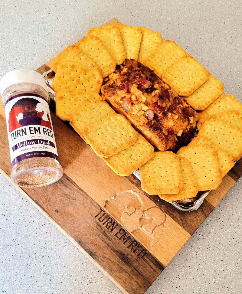 Smokin’ Honey Apple Bacon Cream Cheese served with crackers and seasoning on a wooden board.
