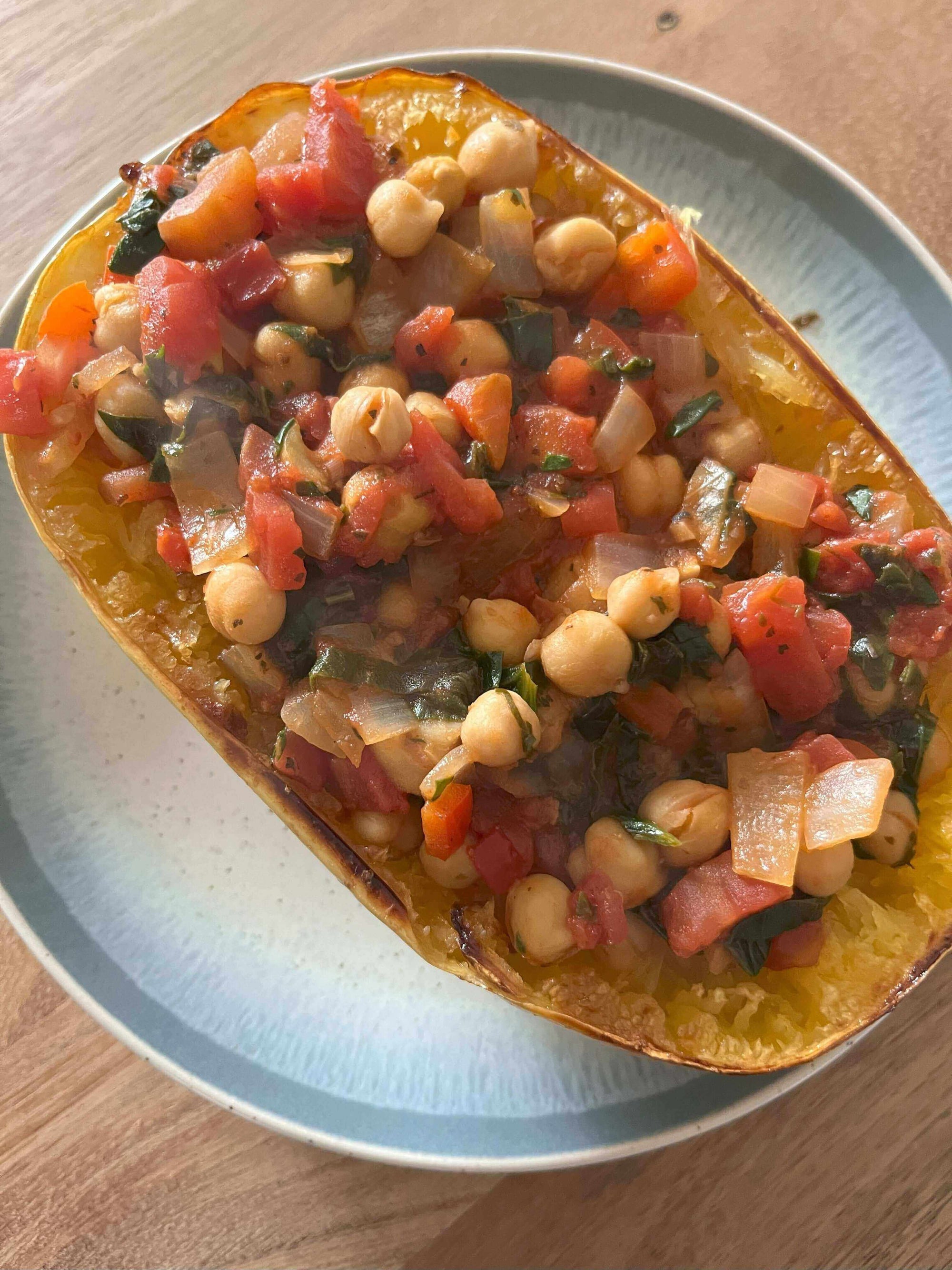 Twirl Me Tender: Tuscan Evening Spaghetti Squash filled with flavorful vegetables and chickpeas on a plate.