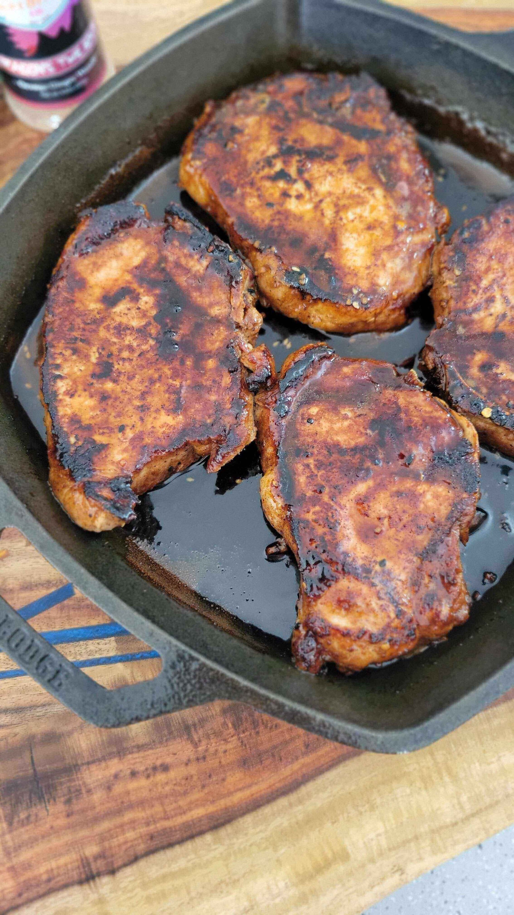 Kiss of the Dragon: Korean-Inspired Pork Chops sizzling in a cast iron skillet, showcasing smoky and spicy flavors.