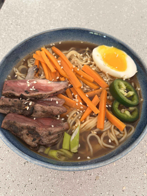 Fiery Dragon Noodles featuring tender steak, spicy jalapeños, and a soft-boiled egg in savory broth.