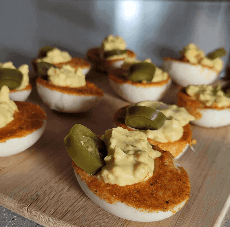 Plate of Spicy Mustard Deviled Eggs with a Kick topped with jalapenos, perfect for any party or gathering.
