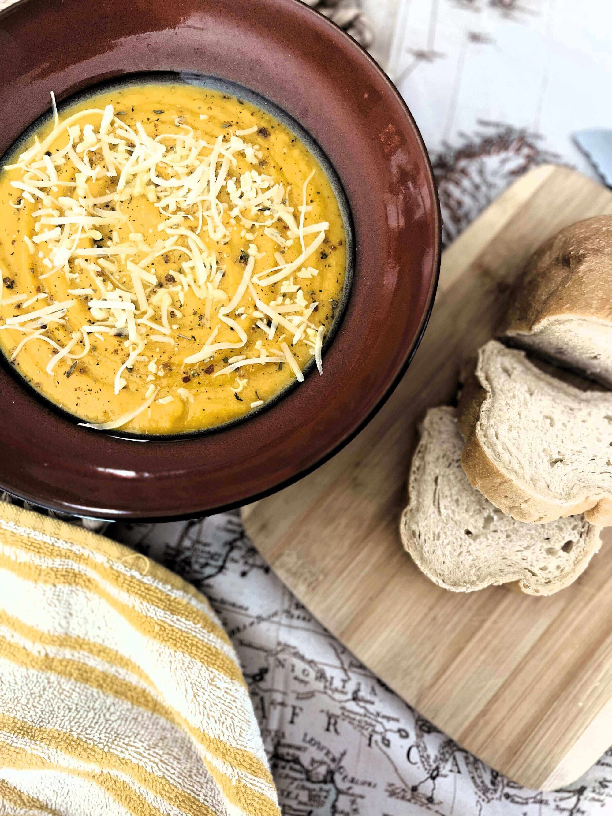 Tuscan Evening Cozy Squash Soup: A Hug in a Bowl topped with cheese, served with slices of bread.