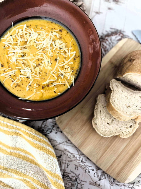 Tuscan Evening Cozy Squash Soup: A Hug in a Bowl topped with cheese, served with slices of bread.
