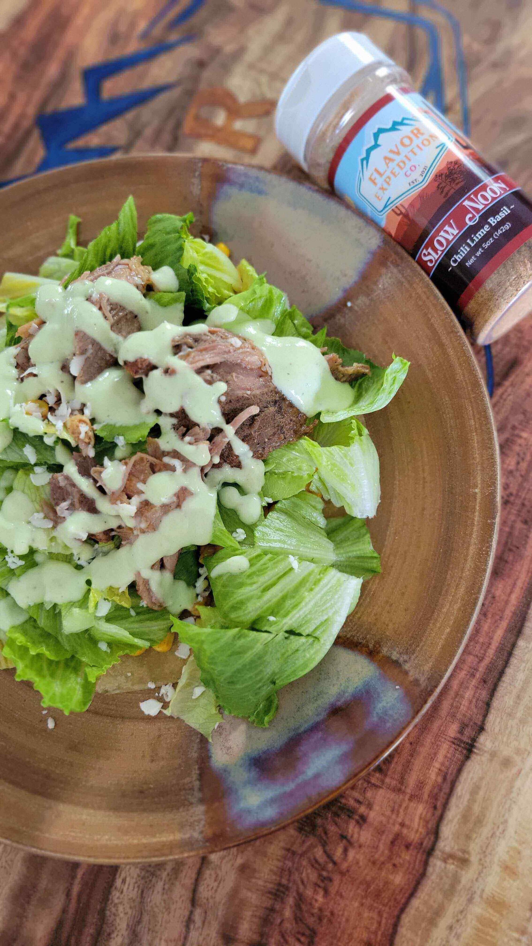 Cafe Rio Sweet Pork Barbacoa Salad (Copycat) topped with creamy dressing and served on a wooden plate.