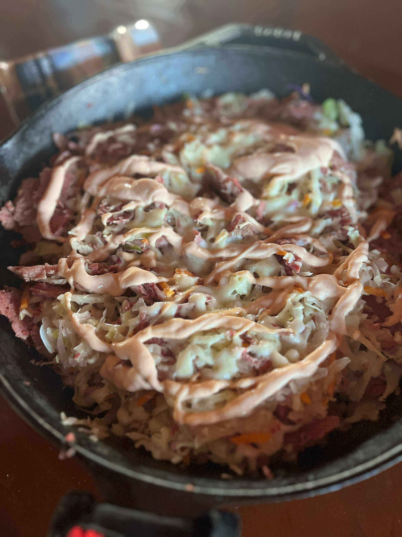 Delicious Reuben in a Bowl served in a cast iron skillet, featuring corned beef, melty Swiss, and creamy dressing.