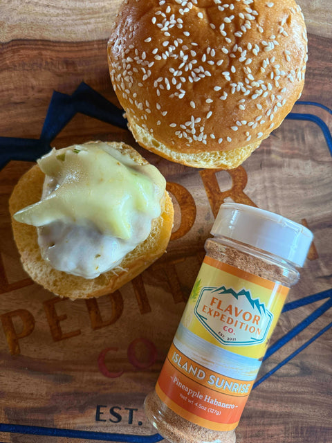 Tropic Like It’s Hot Avocado Turkey Burgers with Island Sunrise seasoning and sesame buns on a wooden table.