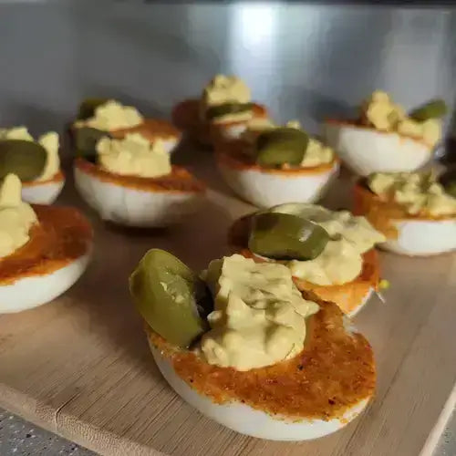Spicy Mustard Deviled Eggs with a Kick topped with jalapeños on a wooden platter.