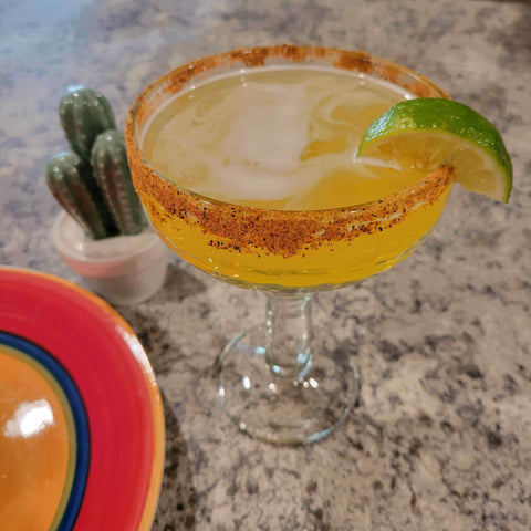 Hot Tropics Margarita garnished with lime and chili-lime rim on a cozy countertop setting.