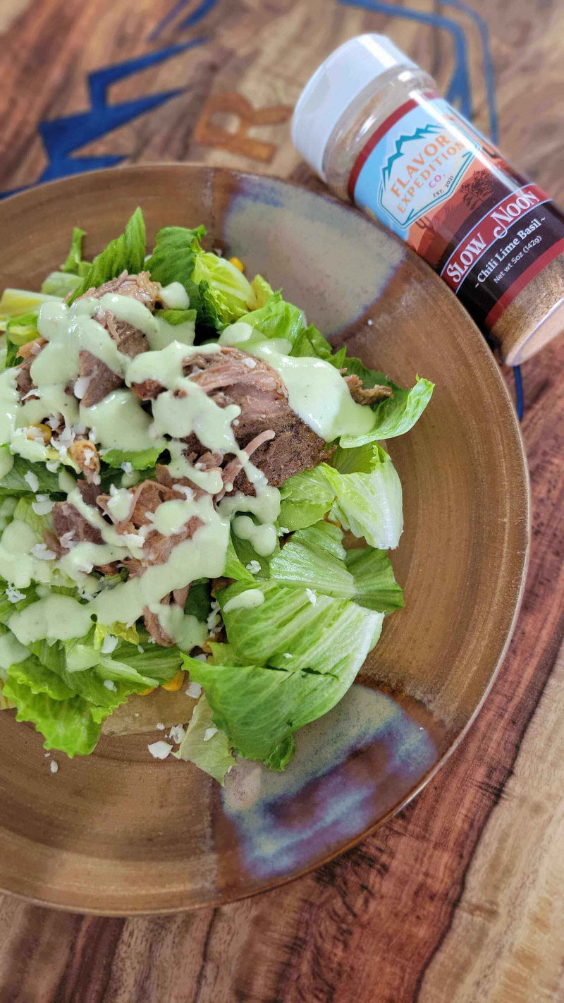 Delicious Copycat Cafe Rio's Sweet Pork Barbacoa Salad with creamy dressing on a wooden table.