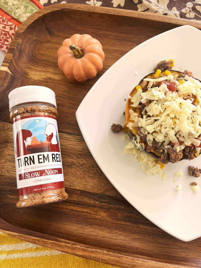 Chili Lime Acorn Squash topped with cheese and ground beef, featuring Slow Noon seasoning on a wooden platter.