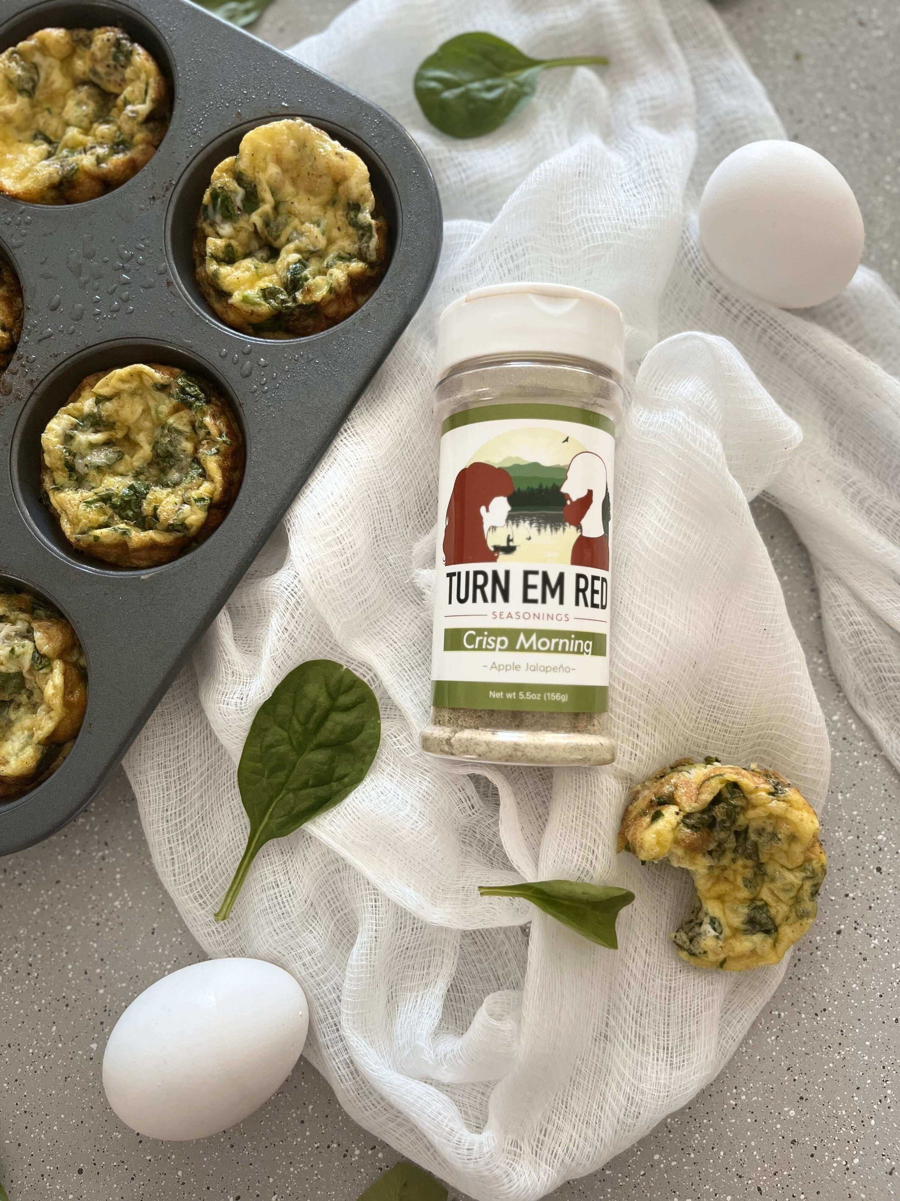 Fresh Sunrise Spinach Egg Muffins in a tray with eggs and seasoning for the perfect healthy breakfast recipe.