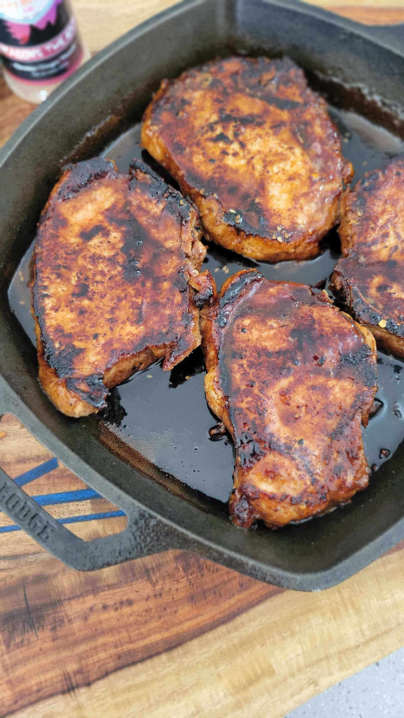 Kiss of the Dragon: Korean-Inspired Pork Chops sizzling in a cast iron skillet, coated in smoky, spicy glaze.