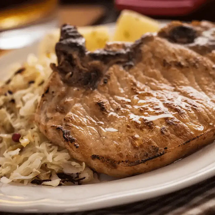 Delicious plate of New Year's Pork and Sauerkraut featuring grilled pork chop and sauerkraut on the side.