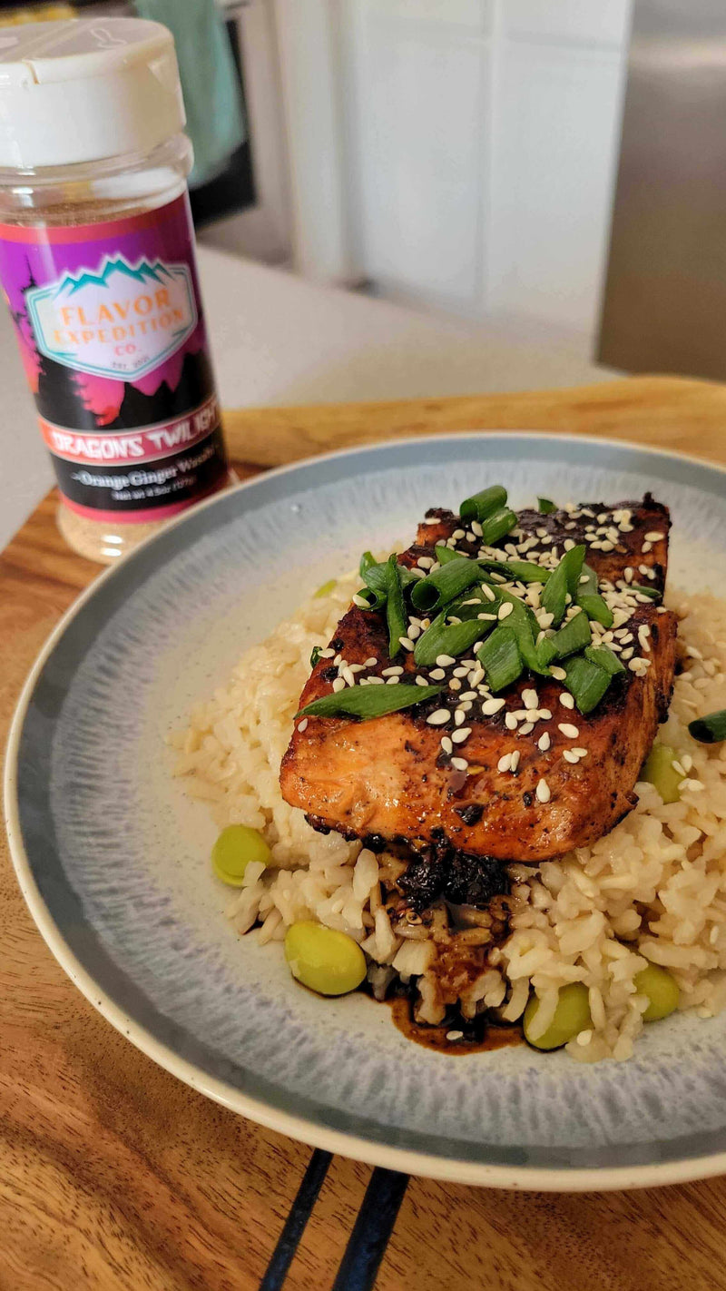 Dragons Twilight Glazed Salmon served on rice with green onions and sesame seeds, featuring the seasoning jar in the background.