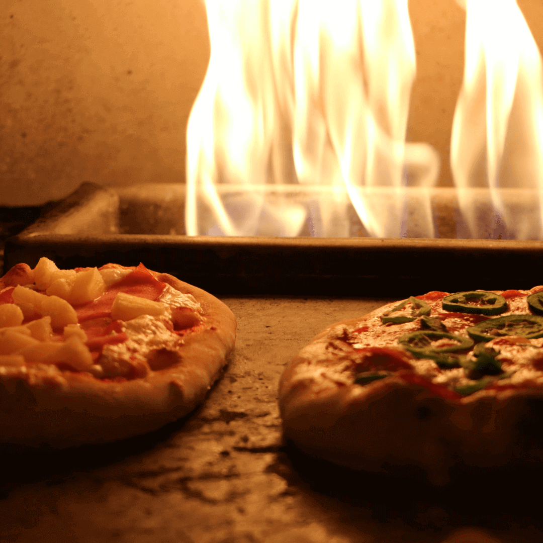 His & Her Ooni Pizza Recipe (feat. Volcanic Sunset) with pizzas baking in a fiery oven.