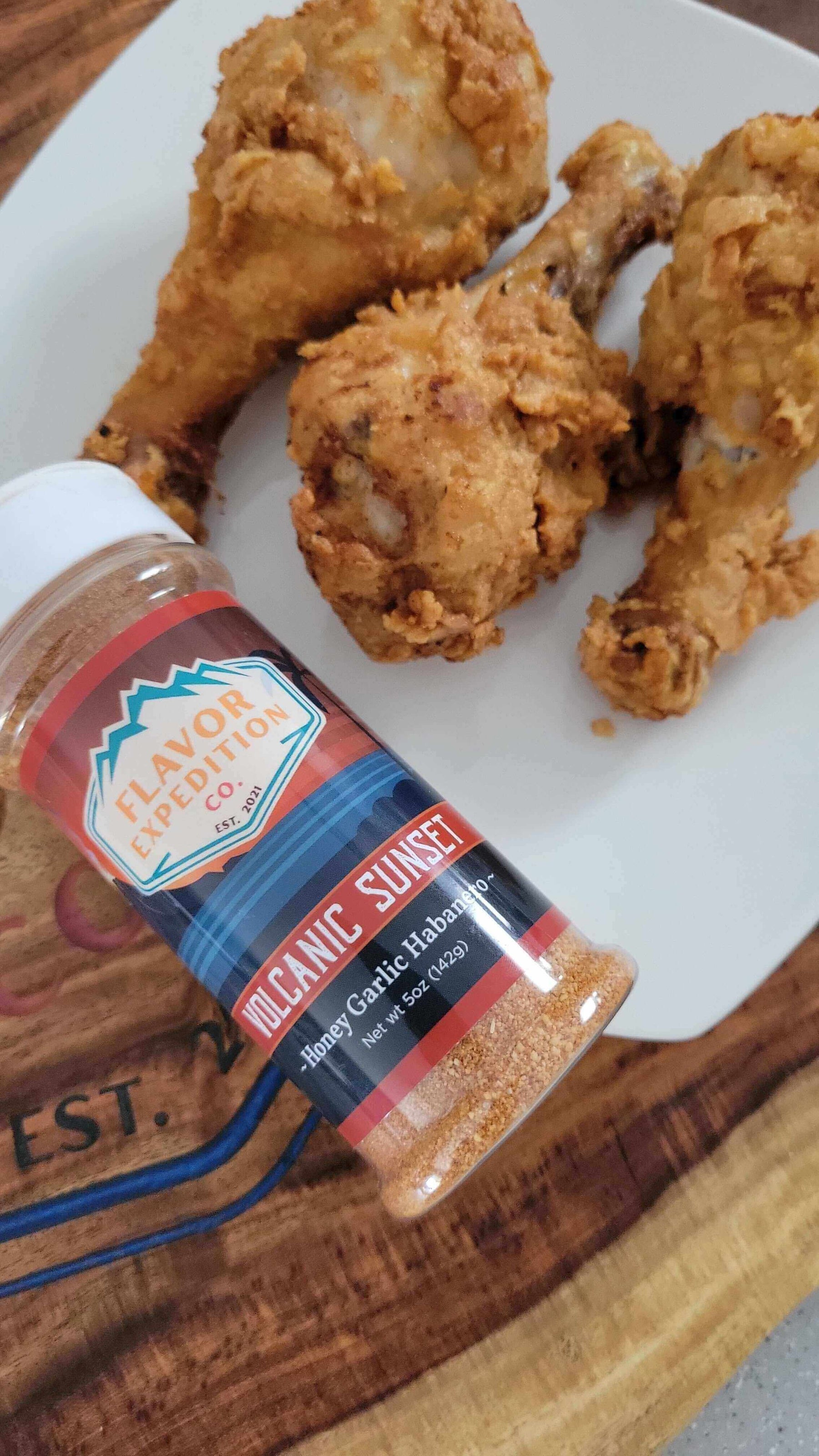 Volcanic Sunset Fried Chicken (Hot Honey Garlic Habanero Style) served with spicy seasoning on a wooden platter.