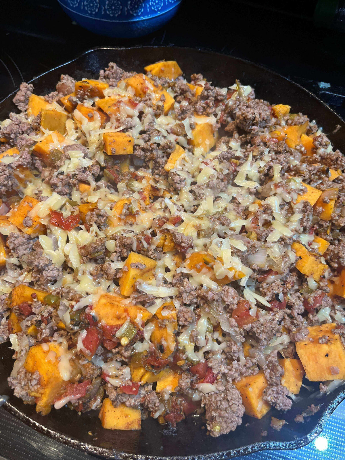 Delicious Southwestern Chuckwagon Skillet featuring ground beef, sweet potatoes, and melted cheese in a cast iron pan.