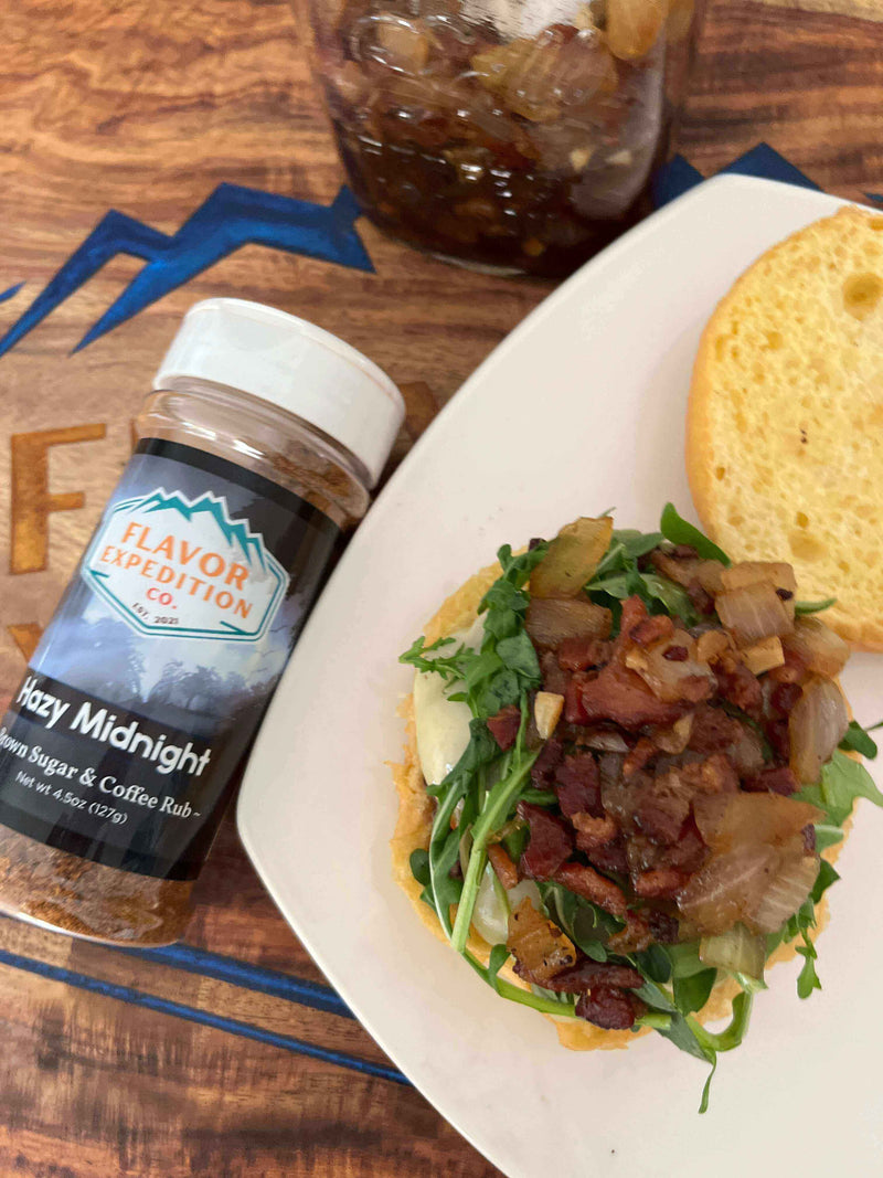 Midnight Ride Blueberry Bison Burger topped with Hazy Midnight seasoning, fresh greens, and crispy bacon on a bun.