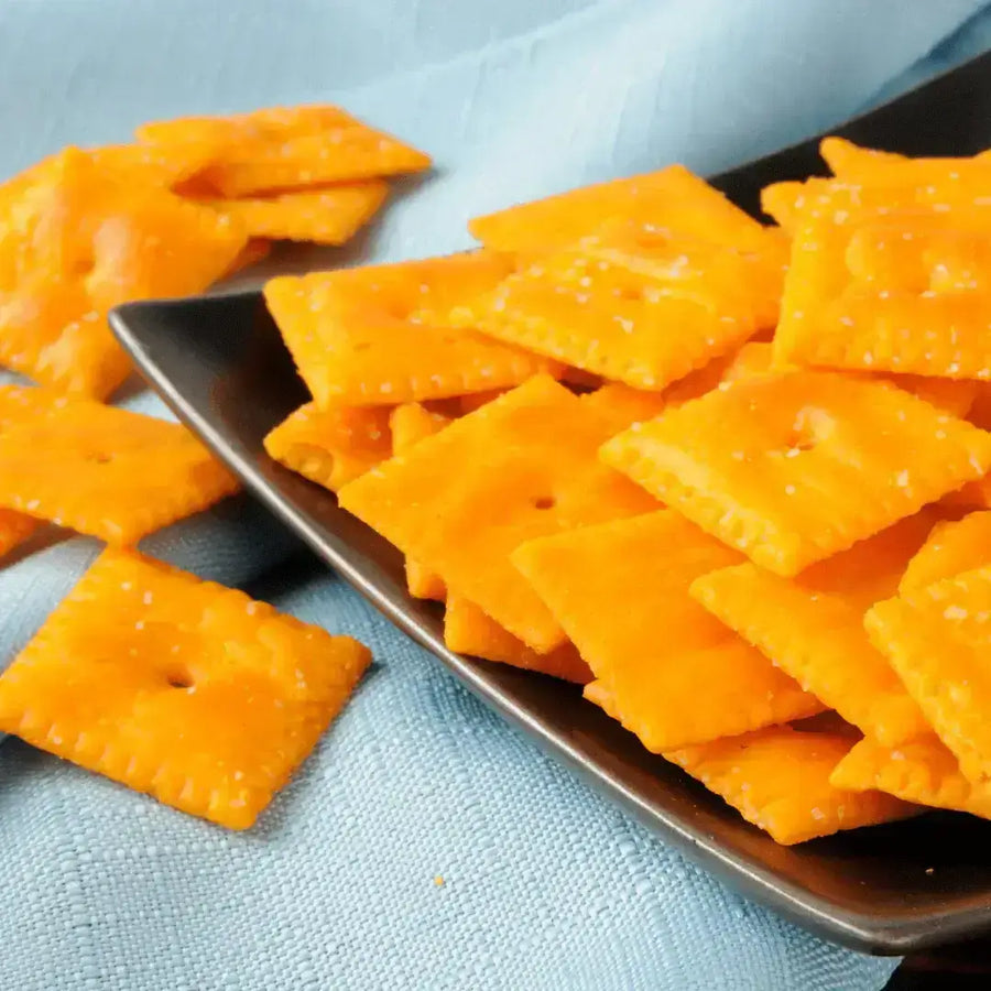 Spicy White Cheddar Cheez-Its (Homemade) arranged on a black plate with a light blue background.