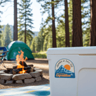 Adventure in Every Bite sticker on a cooler at a campsite with a campfire and tent in the background.