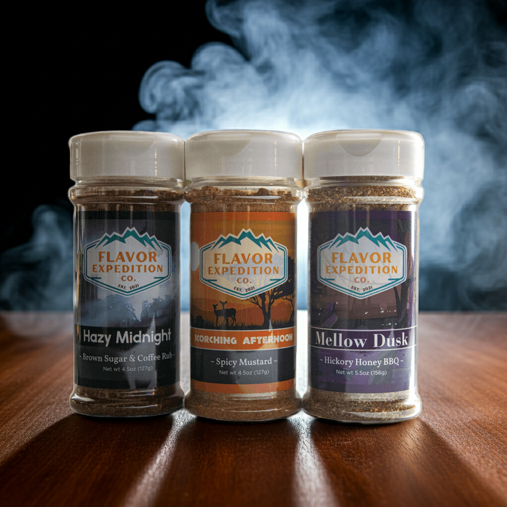 Three jars of Flavor Expedition spices on a wooden surface with smoke in the background.