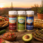 Three jars of Flavor Expedition spices on a wooden table with a desert sunset background.