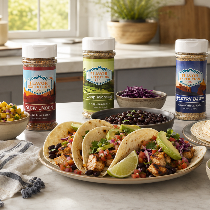 Tacos with various ingredients on a plate, surrounded by jars of Flavor Creation seasoning in a kitchen setting.