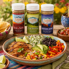 Three bottles of Flavor Expedition seasoning with a bowl of salad and chips on a table outdoors.