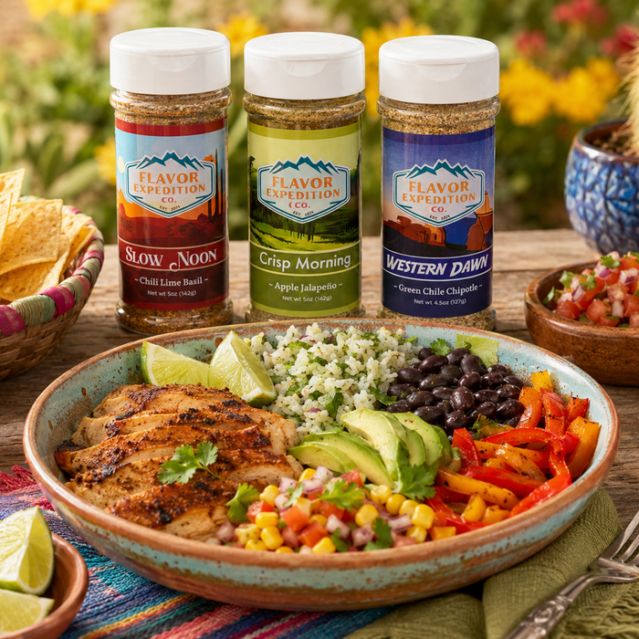 Three bottles of Flavor Expedition seasoning with a bowl of salad and chips on a table outdoors.