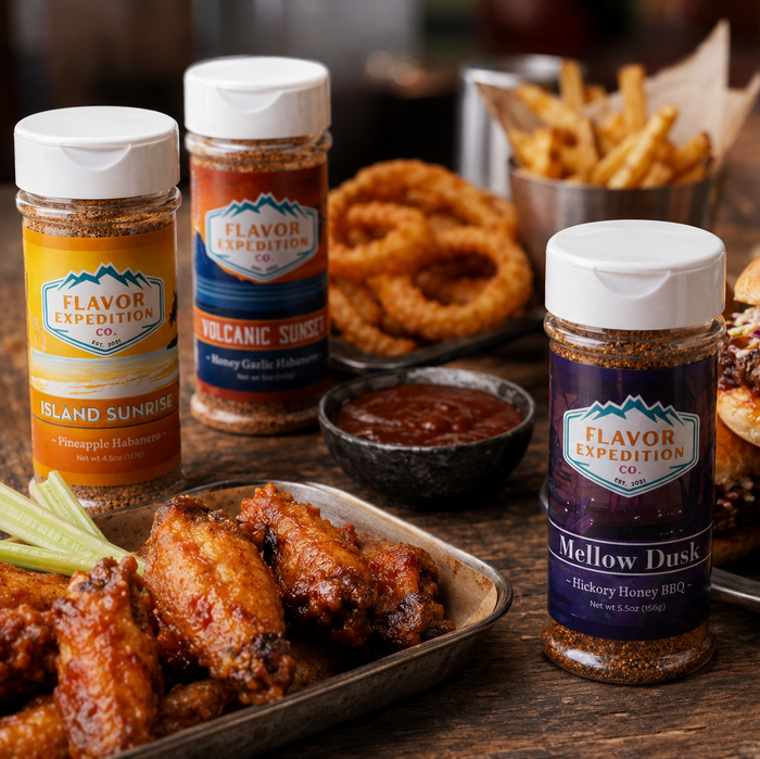 Assorted food items including wings, burgers, fries, and a variety of Flavor Expedition spice jars on a wooden table.