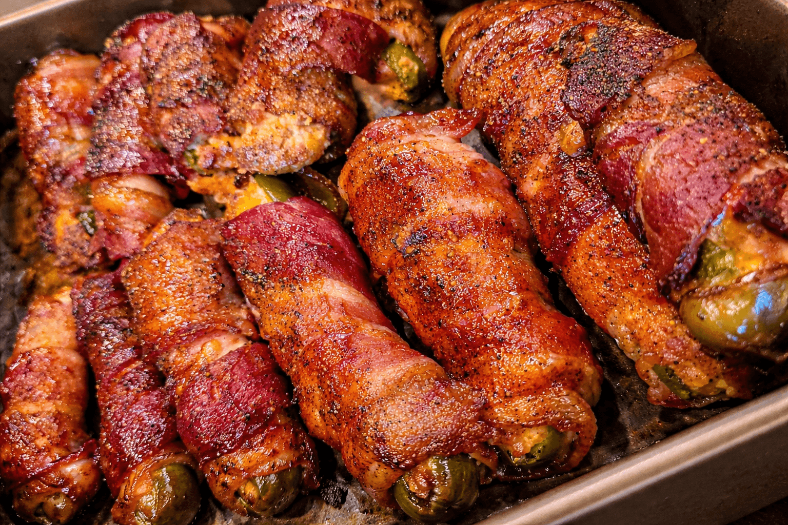 Bacon-wrapped jalapeño peppers on a baking sheet
