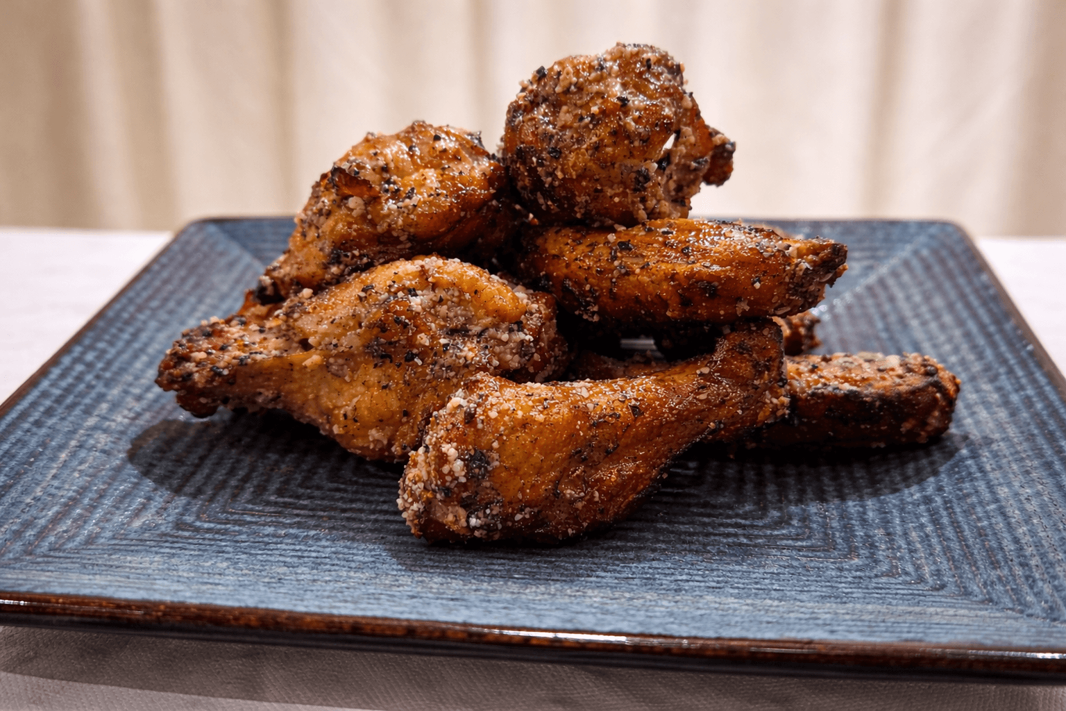 Baked chicken wings on a blue plate with a neutral background