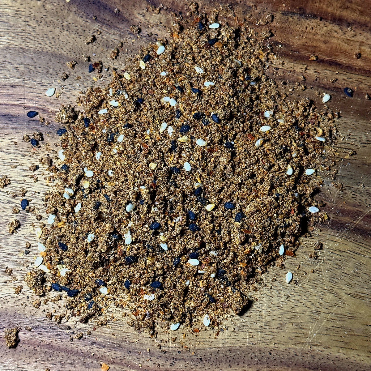 Orange Ginger Wasabi Seasoning scattered on a wooden surface showcasing its vibrant texture and color.