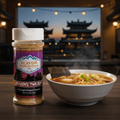 Jar of 'Flavor Expedition Co.' seasoning next to a bowl of noodles with a blurred background of traditional Chinese architecture.