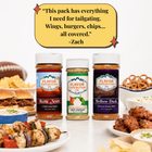Three Flavor Expedition Co. seasoning bottles displayed on a white surface with food props around them: a burger, chips, pretzels, grilled skewers, wings, and a bowl of dip.