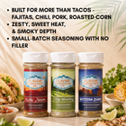 Three seasoning jars with labels on a table with food in the background