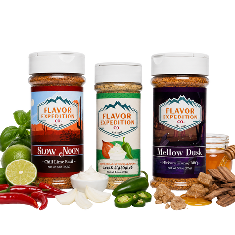 Three spice seasoning bottles from Flavor Expedition Co. are displayed on a white background with their corresponding flavor ingredients arranged around them.