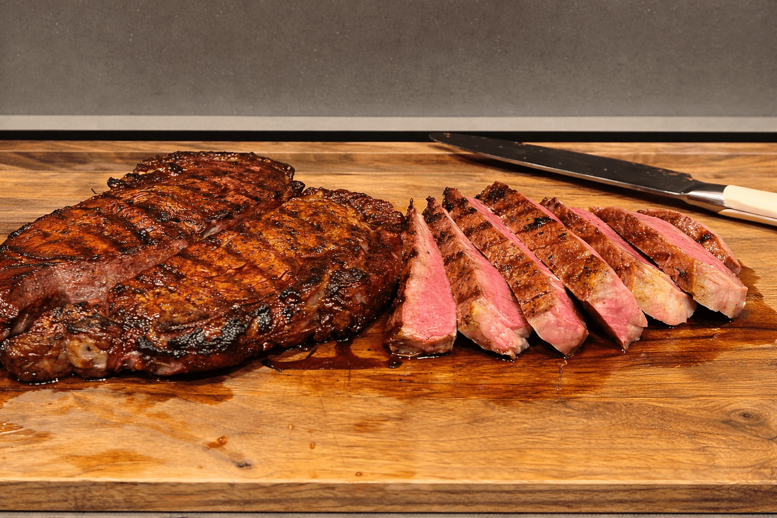 Steak with a slice cut, on a wooden cutting board with a knife.