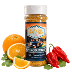 Hot Rod Howie's seasoning bottle beside oranges, cilantro and red peppers.