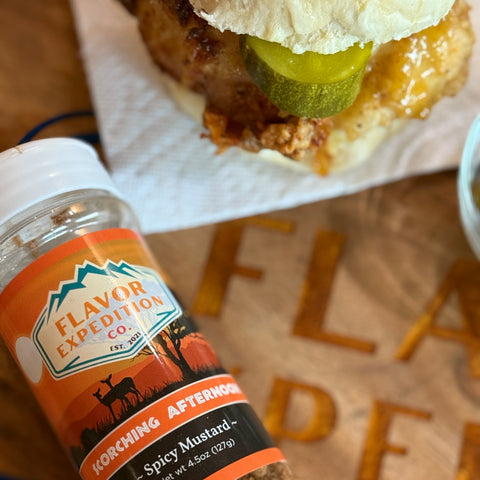 Bottle of Korching Afternoon spicy mustard next to a sandwich, highlighting bold flavors and culinary adventure.