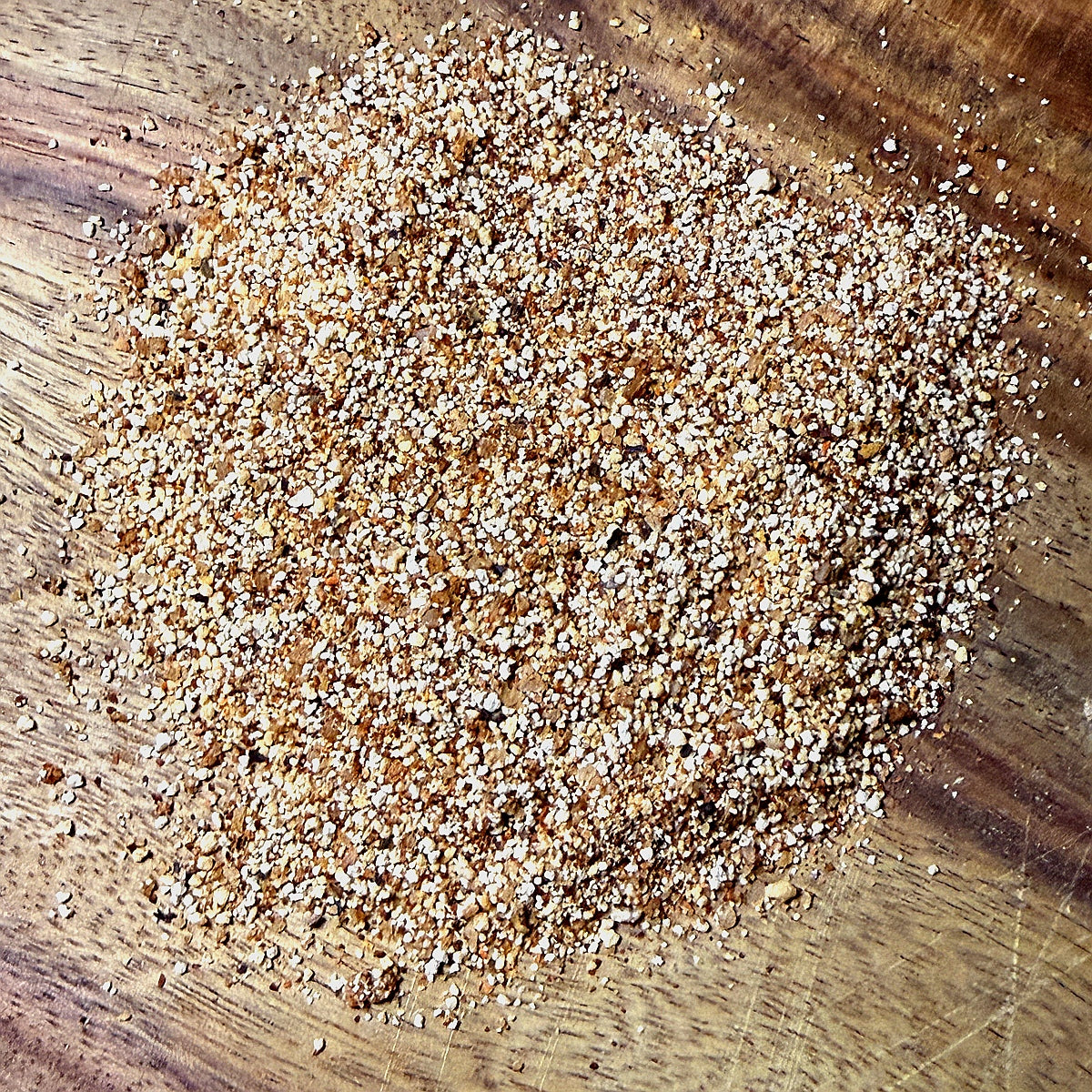Hickory Honey BBQ Seasoning sprinkled on a wooden surface, showcasing its rich texture and color for BBQ enthusiasts.
